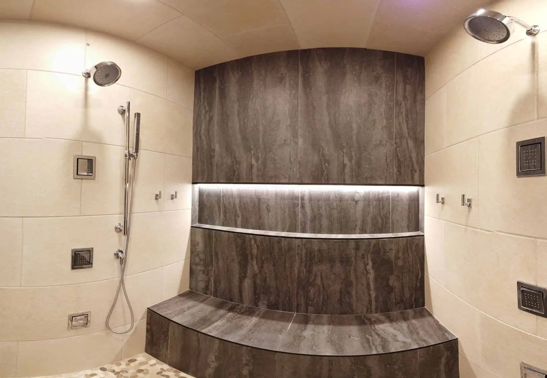 Curved double-head tile shower with lit niche and built-in bench