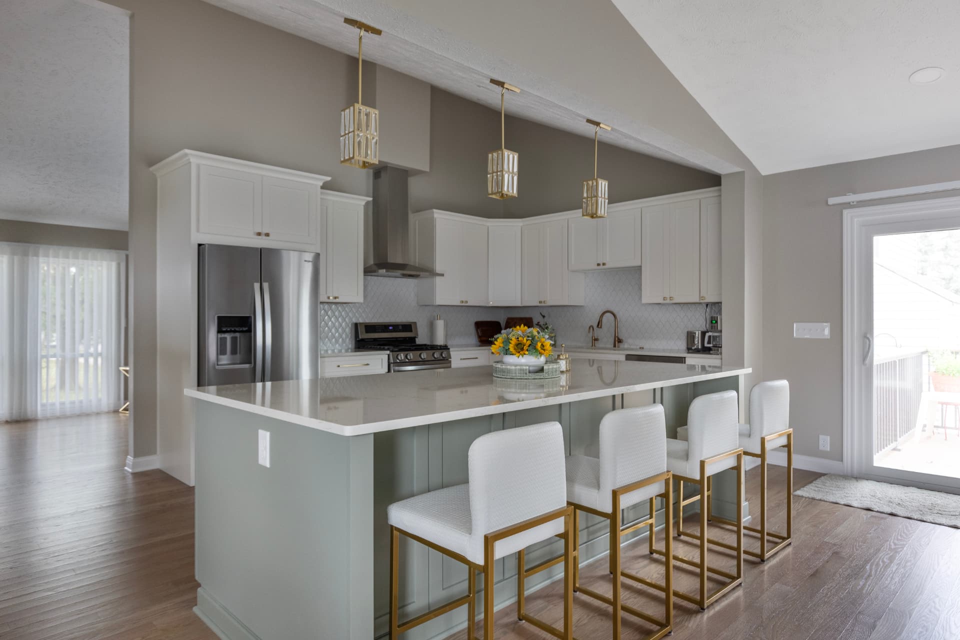 Open Omaha kitchen remodel with white cabinetry, a sage island, brass accents, and oak hardwood floors