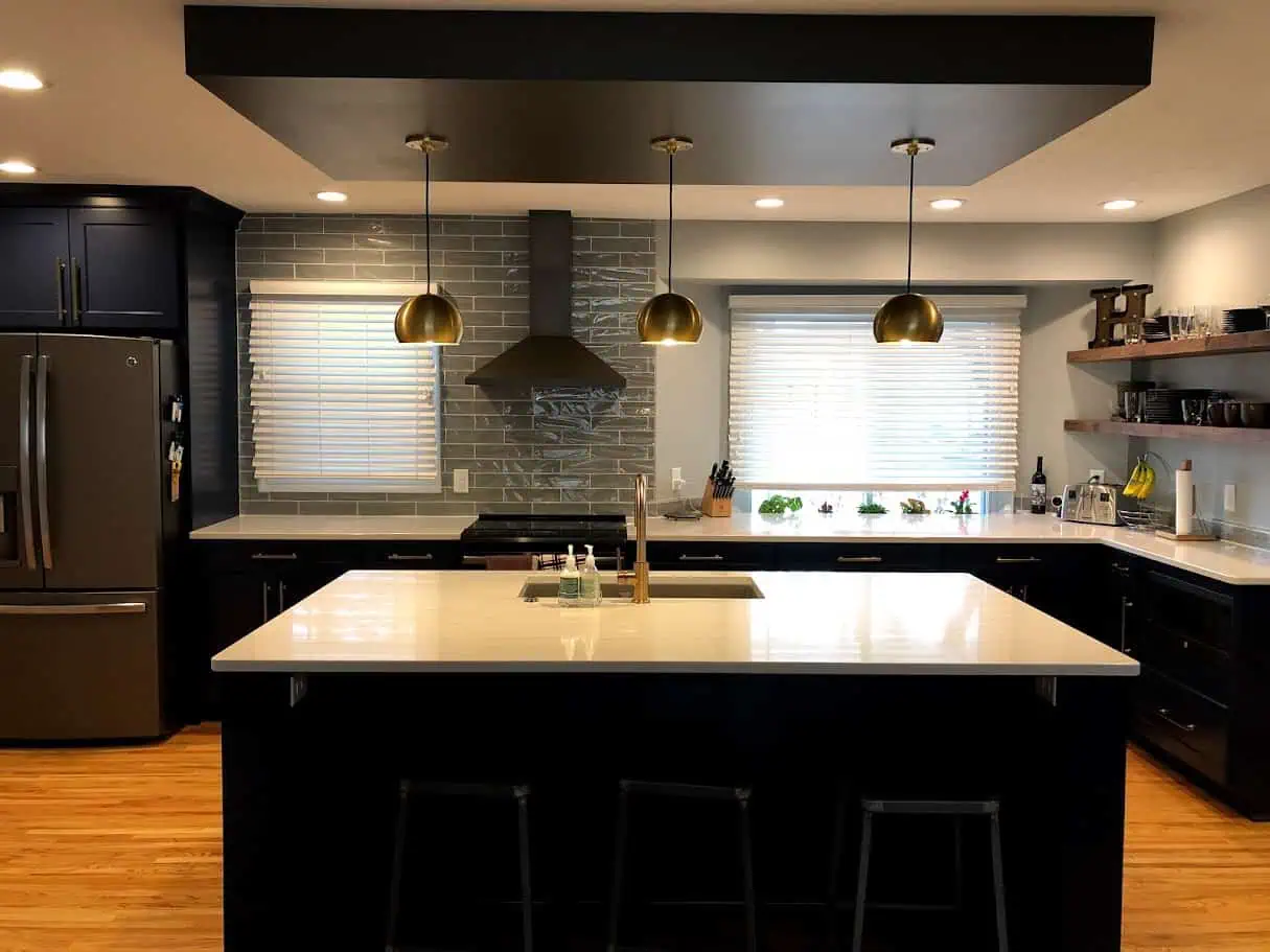 Black shaker kitchen with waterfall quartz island and gold globe pendants